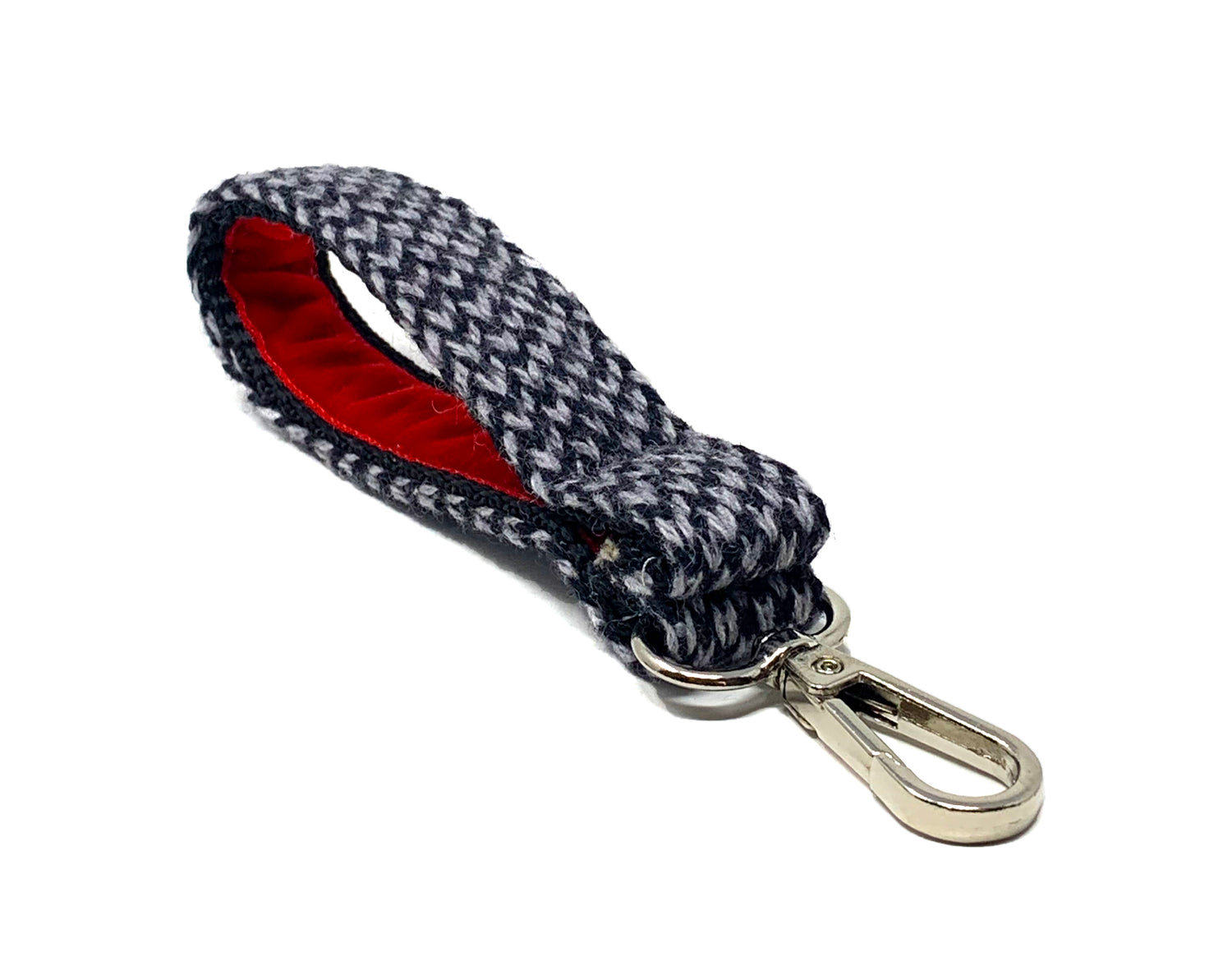 Black & grey knitted key ring with a red velvet inner lining and a metal clip. The key ring is placed on a white background. 